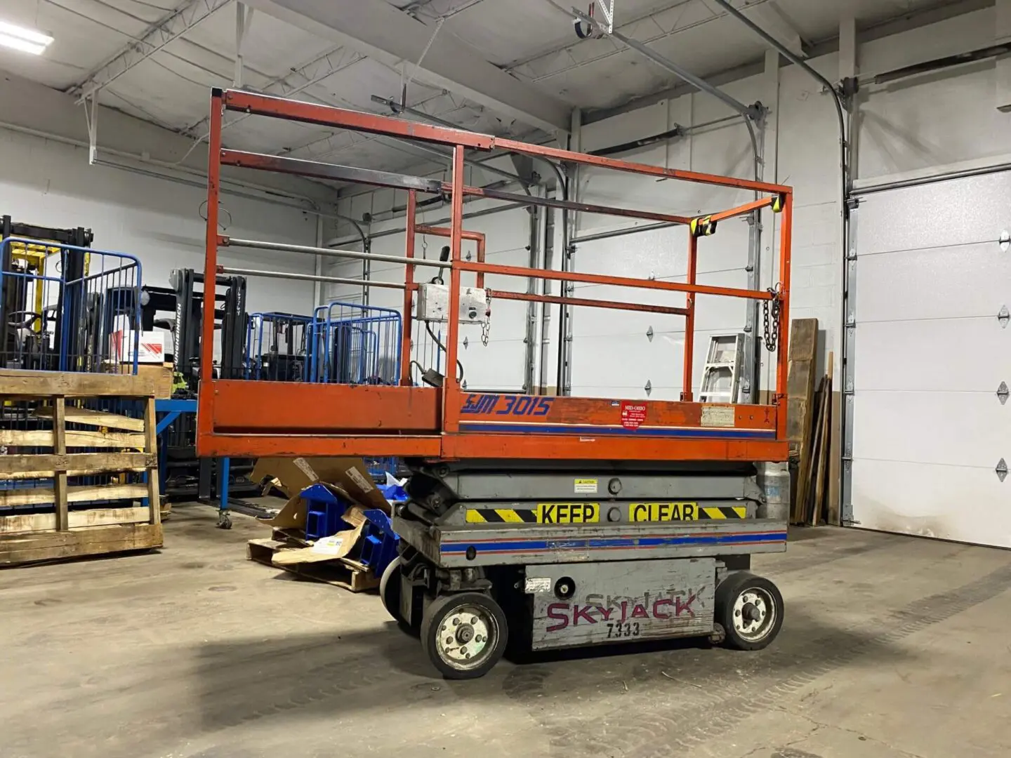 Orange scissor lift in warehouse setting.