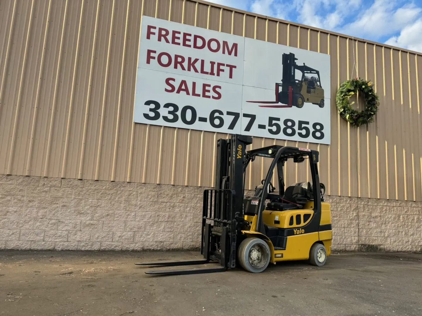 Yellow forklift parked near sales sign.