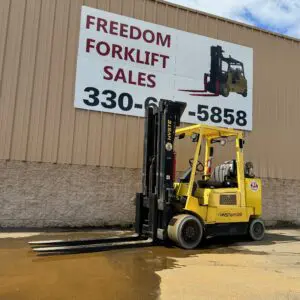 Yellow forklift parked outside sales building.