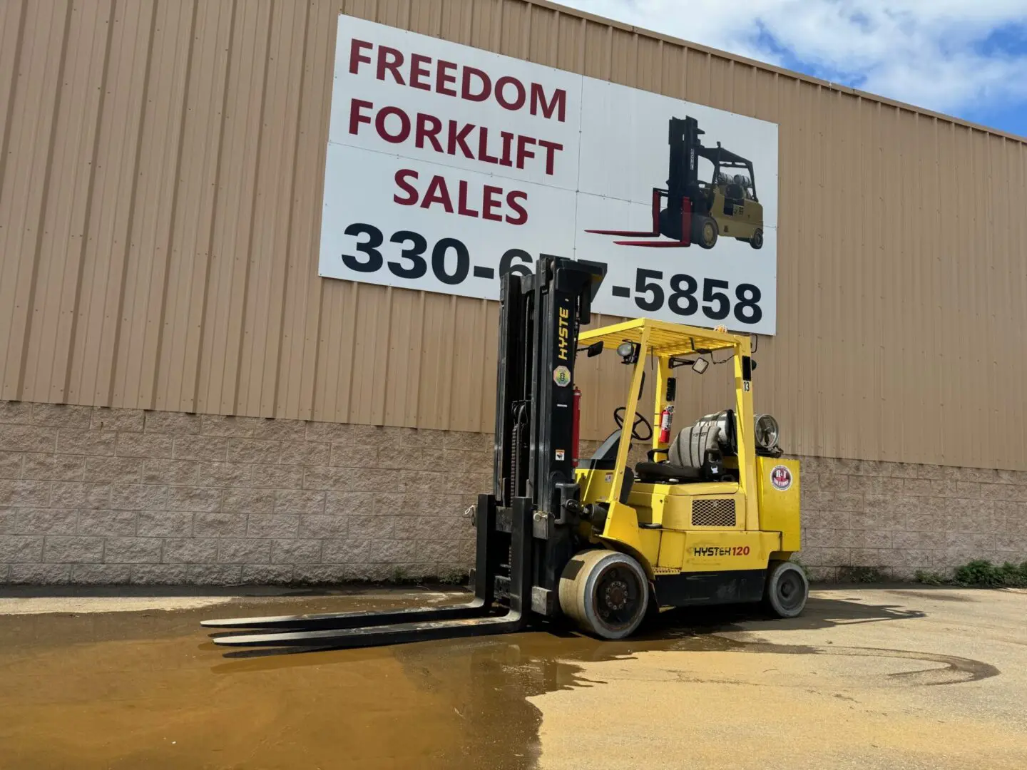 Yellow forklift parked outside sales building.