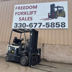 Forklift parked under sales sign outdoors.