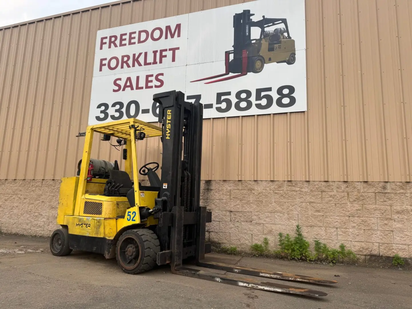 Yellow forklift in front of sales sign.