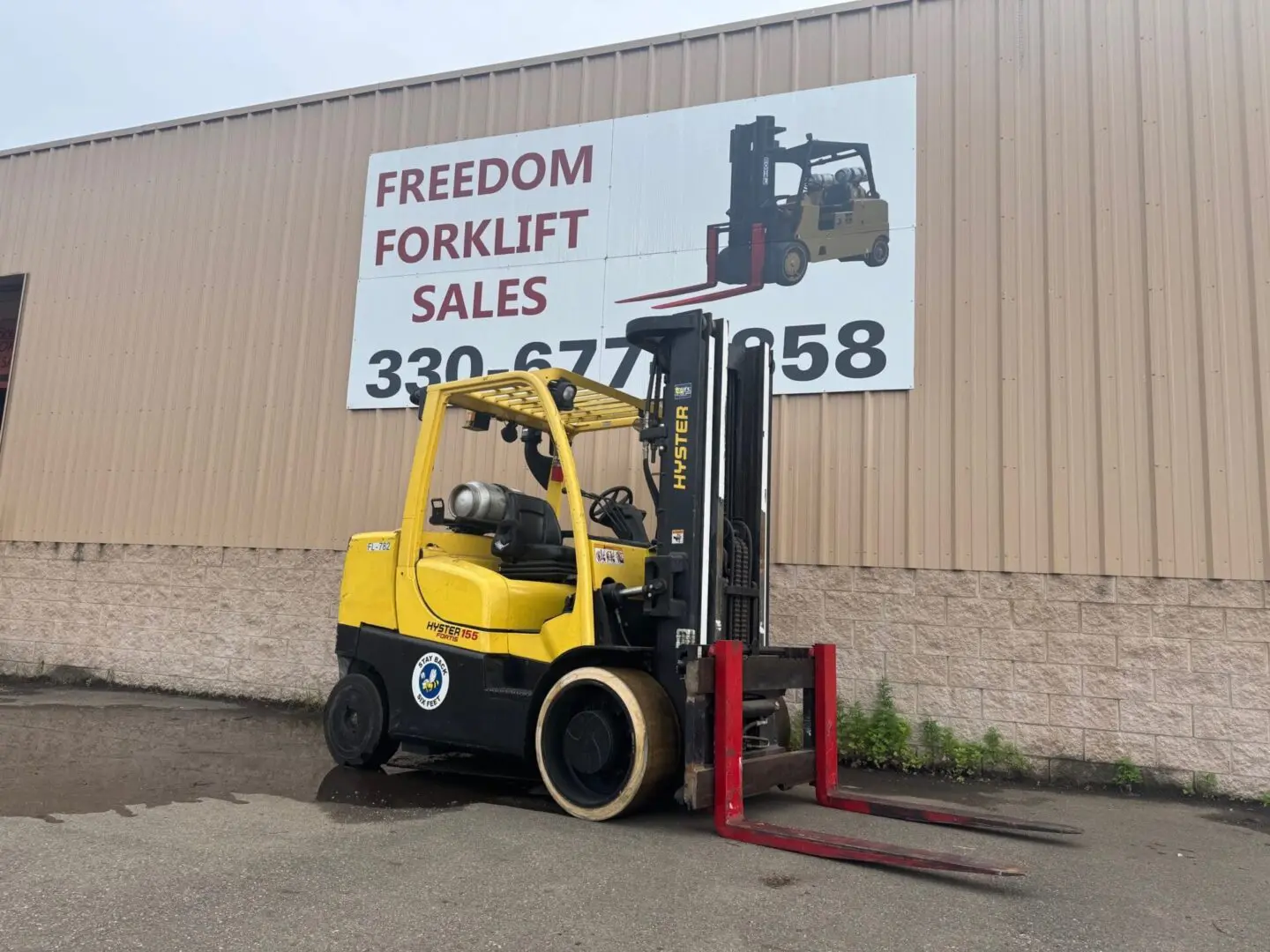 Yellow forklift parked near sales sign.