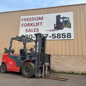 Red forklift parked by sales sign.
