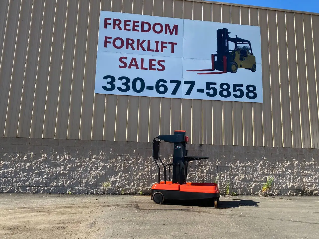 Forklift in front of sales company sign.
