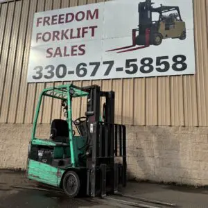 Green forklift displayed outside sales building.