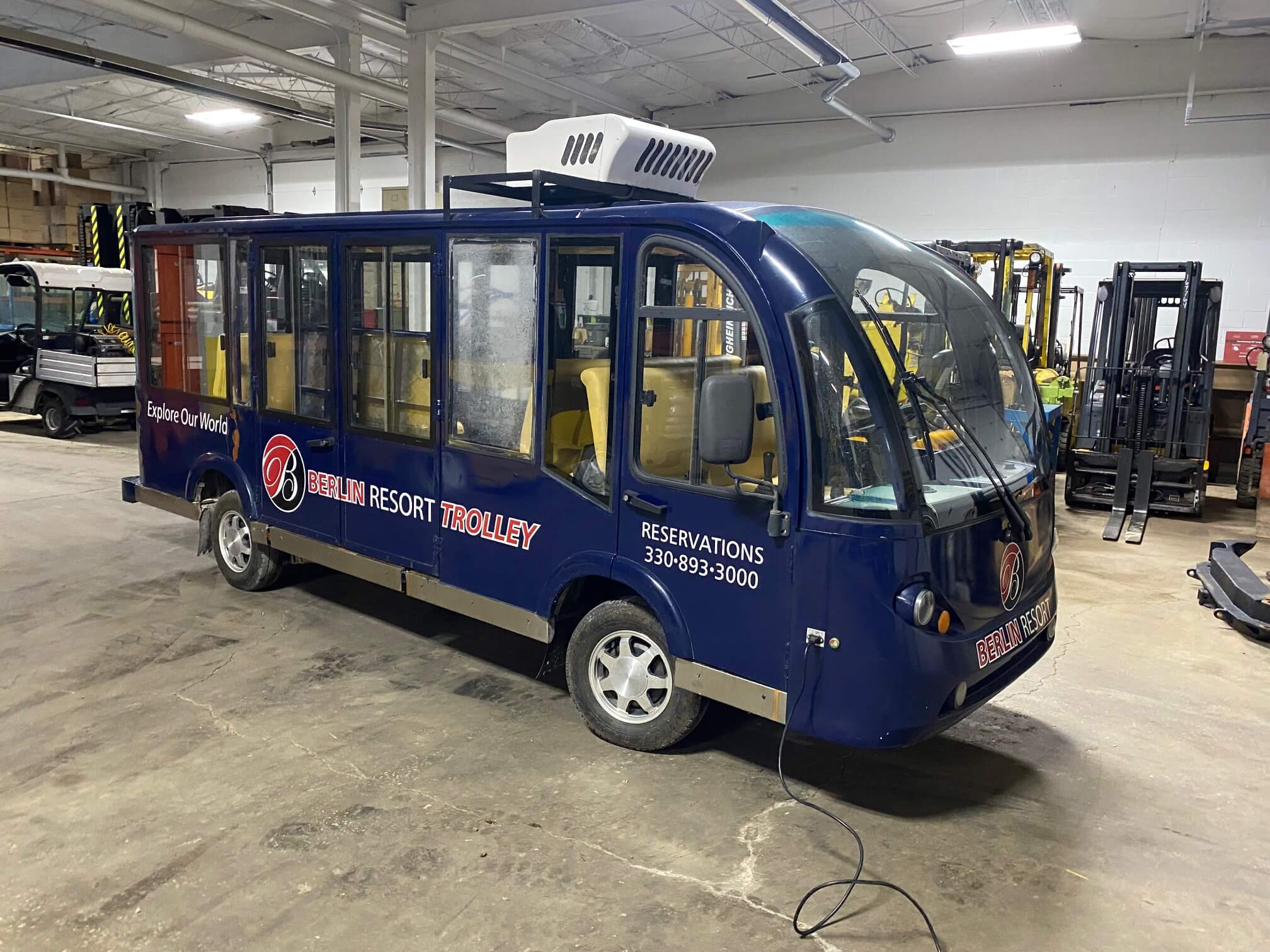 A blue bus is parked in the garage.