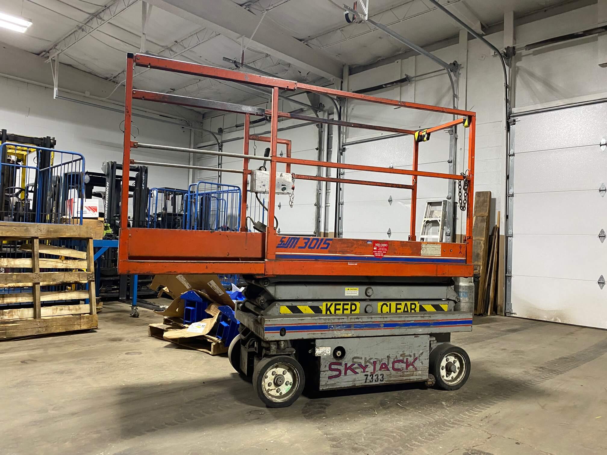 A scissor lift in an industrial setting with boxes.