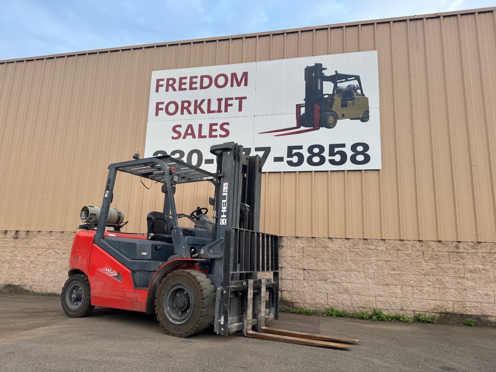 Red forklift parked near sales sign.